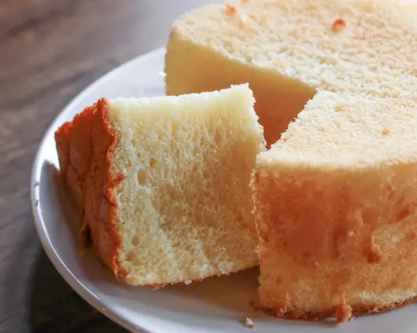 Il segreto per torte alte e soffici: una fetta di torta soffice e dorata su un piatto bianco, pronta per essere gustata.