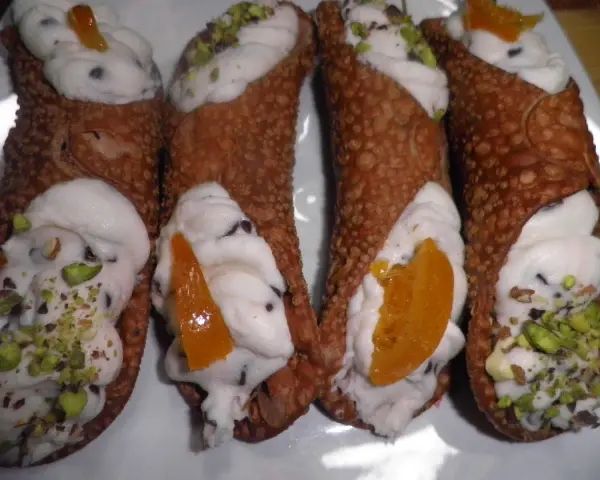Cannoli siciliani con ripieno cremoso, gocce di cioccolato e pistacchi. Una ricetta semplice per un dolce irresistibile.