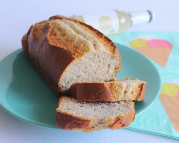 Fetta di banana bread light su piatto turchese, con bottiglia e tovaglioli a tema gelato sullo sfondo.