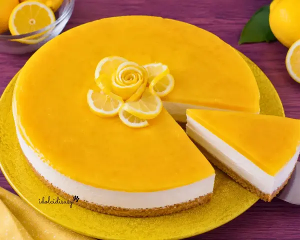 Cheesecake al limone con decorazione di fettine e rosa di limone. Una fetta è già servita.