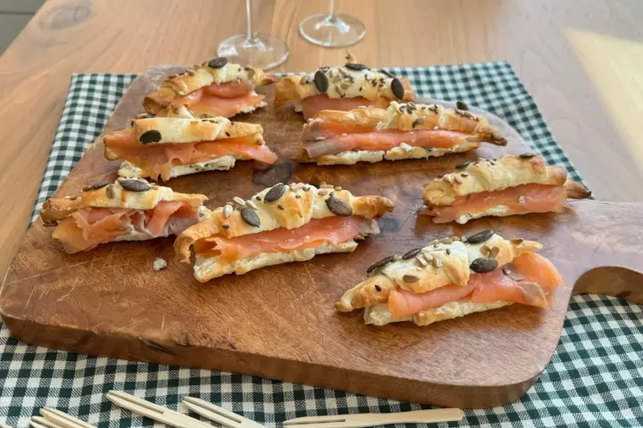 Cornetti di pasta sfoglia ripieni di salmone affumicato e formaggio cremoso, guarniti con semi.