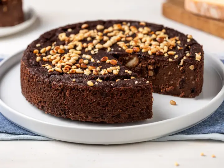 Torta paesana al cioccolato, ricca e umida, guarnita con pinoli tostati. Un dolce rustico che sa di casa.