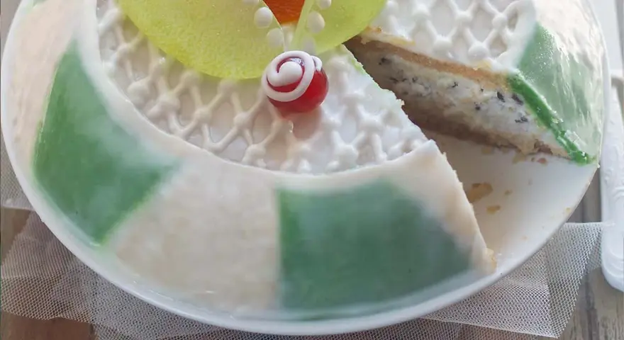 Una fetta di cassata siciliana palermitana, con decorazioni in glassa bianca e canditi colorati, mostra il suo ripieno cremoso.