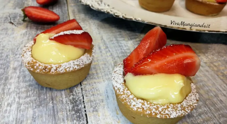 Deliziosi cestini alla frutta con crema pasticcera e fragole fresche, spolverati di zucchero a velo.