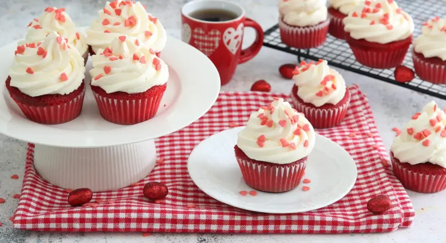 Deliziosi muffin red velvet con glassa bianca e cuoricini rossi, perfetti per San Valentino.