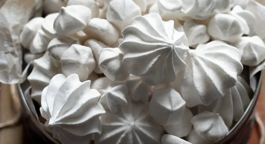 Un cesto pieno di meringhe soffici, perfette per la tua ricetta. Dolci e leggere, un piacere da gustare.