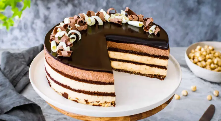 Una magnifica torta sette veli, con strati di mousse al cioccolato e crema, ricoperta da glassa lucida e riccioli di cioccolato.