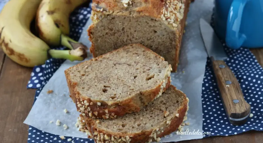 Fetta di banana bread senza burro, soffice e profumato, con croccante copertura di frutta secca. Perfetto per la colazione.