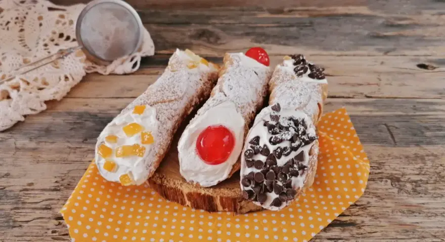 Cannoli siciliani decorati con canditi, ciliegie e gocce di cioccolato, pronti per essere gustati. Ingredienti cannolo siciliano perfetti.