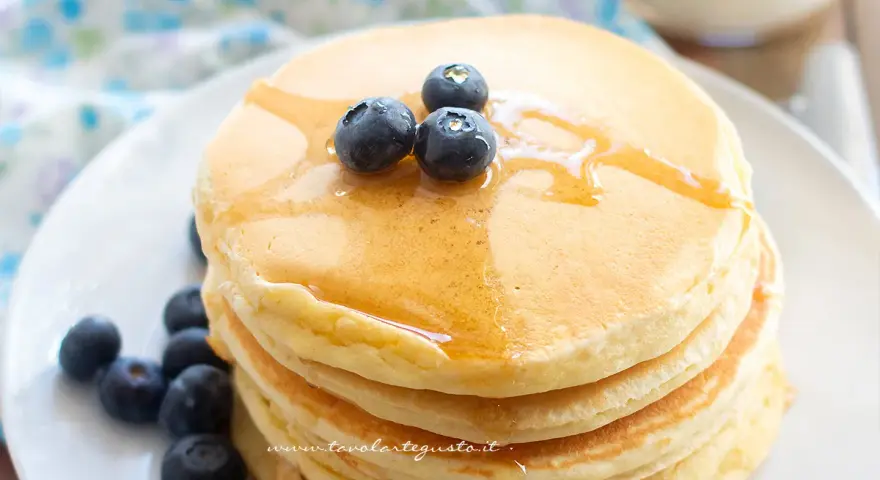 Pancakes soffici con albumi, guarniti con mirtilli freschi e sciroppo d'acero. Un dolce inizio di giornata.