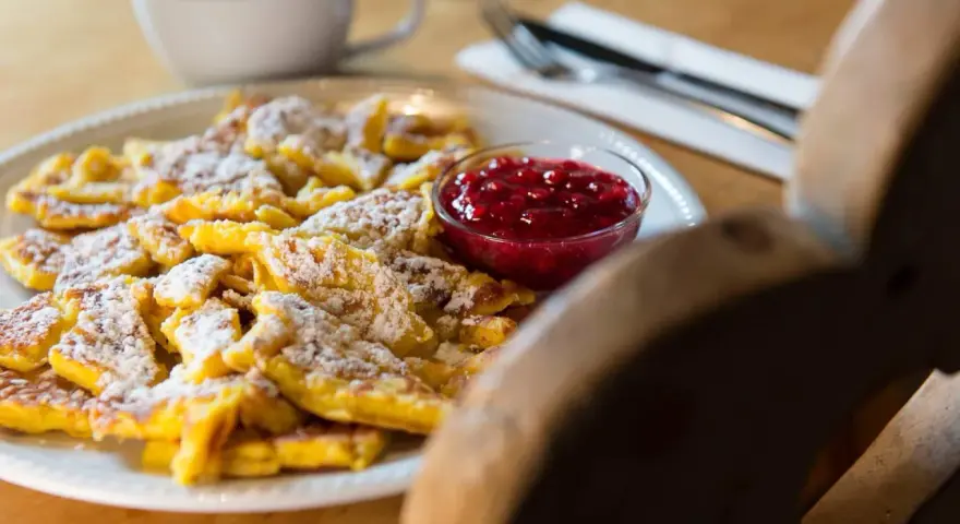 Frittata dolce tirolese cosparsa di zucchero a velo, servita con marmellata di mirtilli rossi.