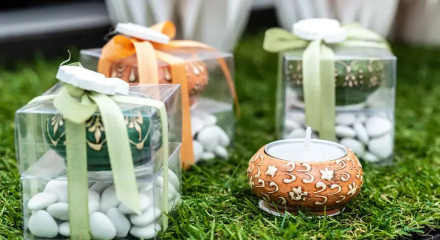 Confezioni regalo con confetti bianchi, candela e decorazioni floreali. Il significato dei confetti, augurio di dolcezza e prosperità.