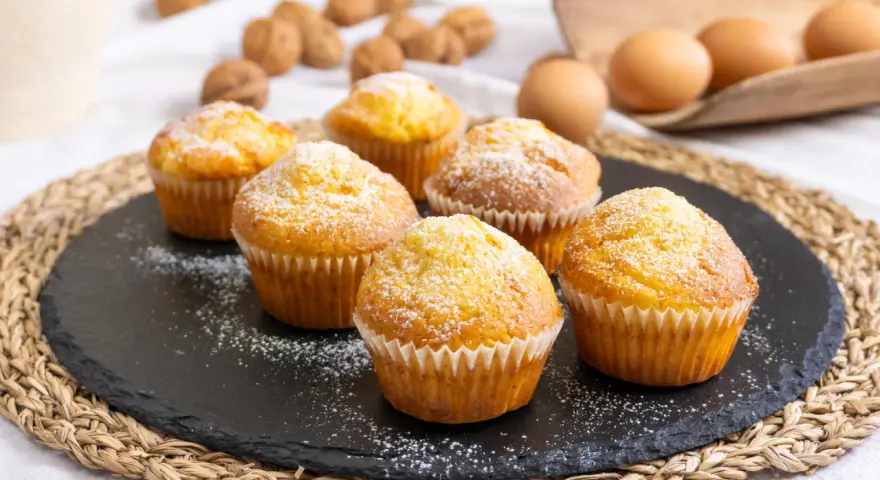 Sei muffin allo yogurt spolverati di zucchero a velo, pronti per essere gustati.