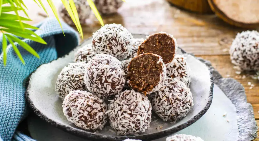 Praline al cioccolato facili e veloci, ricoperte di cocco grattugiato. Un morso rivela un interno morbido e goloso.