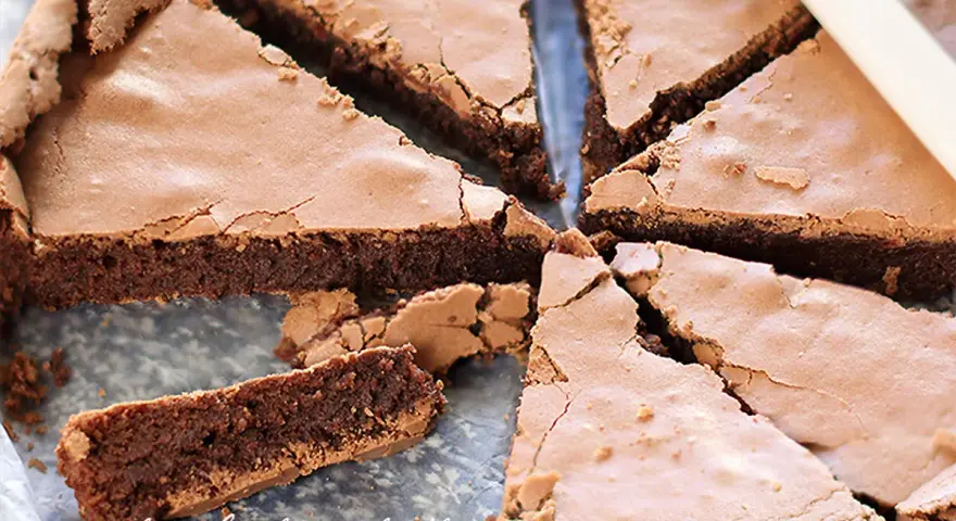 Torta tenerina con cuore morbido, tagliata a fette triangolari. La superficie è leggermente screpolata, rivelando la consistenza umida e golosa.