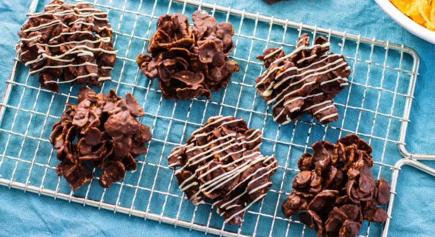 Dolcetti croccanti al cioccolato, simili a rose del deserto ricetta, su una griglia di raffreddamento. Alcuni sono decorati con cioccolato bianco.
