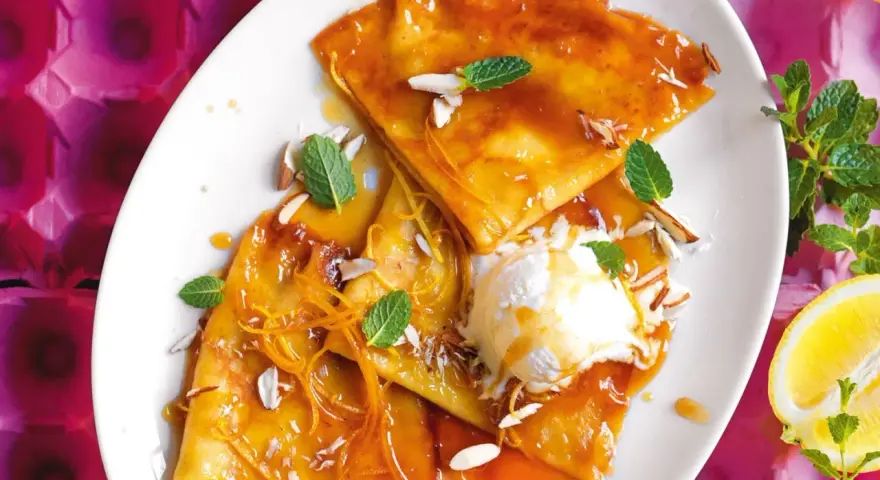 Crepes flambé con gelato, mandorle e scorza d'arancia. Ecco cosa serve per fare le crepes: farina, uova, latte, burro e zucchero.