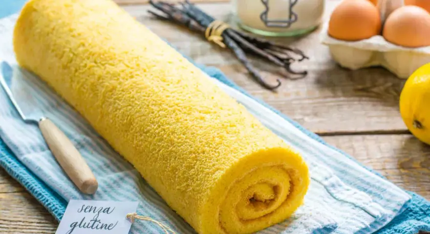 Rotolo giallo soffice, un delizioso pasta biscotto senza glutine, pronto per essere gustato. Ingredienti freschi sullo sfondo.