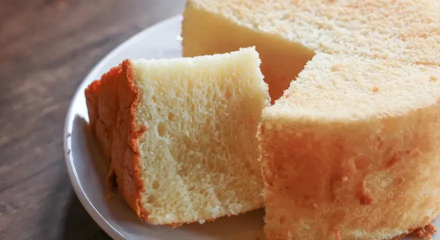 Il segreto per torte alte e soffici: una fetta di torta soffice e dorata su un piatto bianco, pronta per essere gustata.
