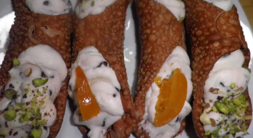 Cannoli siciliani con ripieno cremoso, gocce di cioccolato e pistacchi. Una ricetta semplice per un dolce irresistibile.