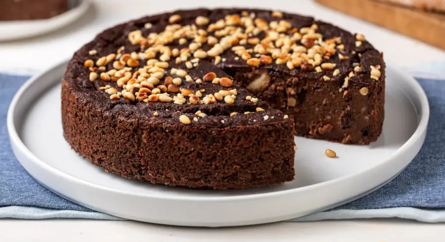 Torta paesana al cioccolato, ricca e umida, guarnita con pinoli tostati. Un dolce rustico che sa di casa.