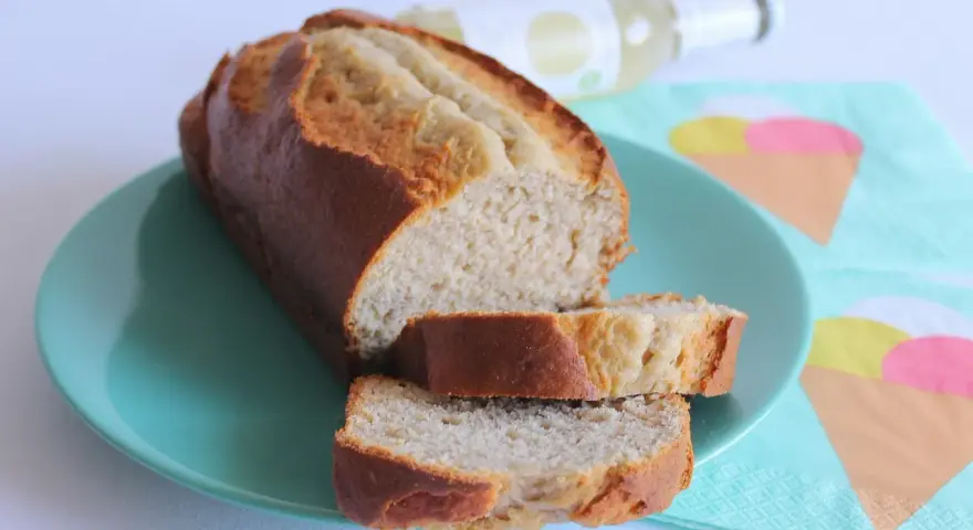 Fetta di banana bread light su piatto turchese, con bottiglia e tovaglioli a tema gelato sullo sfondo.