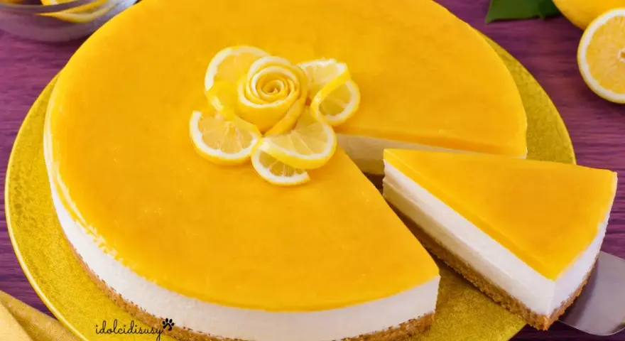 Cheesecake al limone con decorazione di fettine e rosa di limone. Una fetta è già servita.