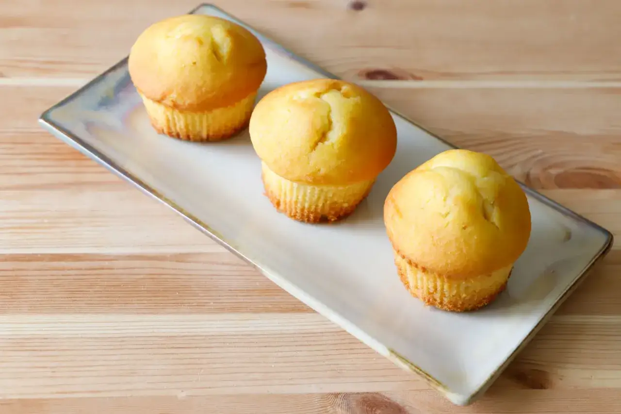 Tre muffin allo yogurt dorati su un piatto rettangolare, pronti per essere gustati.