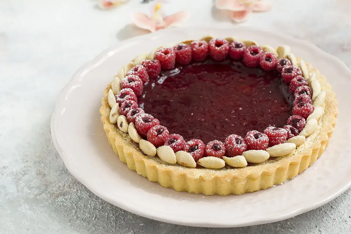 Torta con frangipane, lamponi freschi e mandorle. Una deliziosa ricetta per un dolce perfetto.