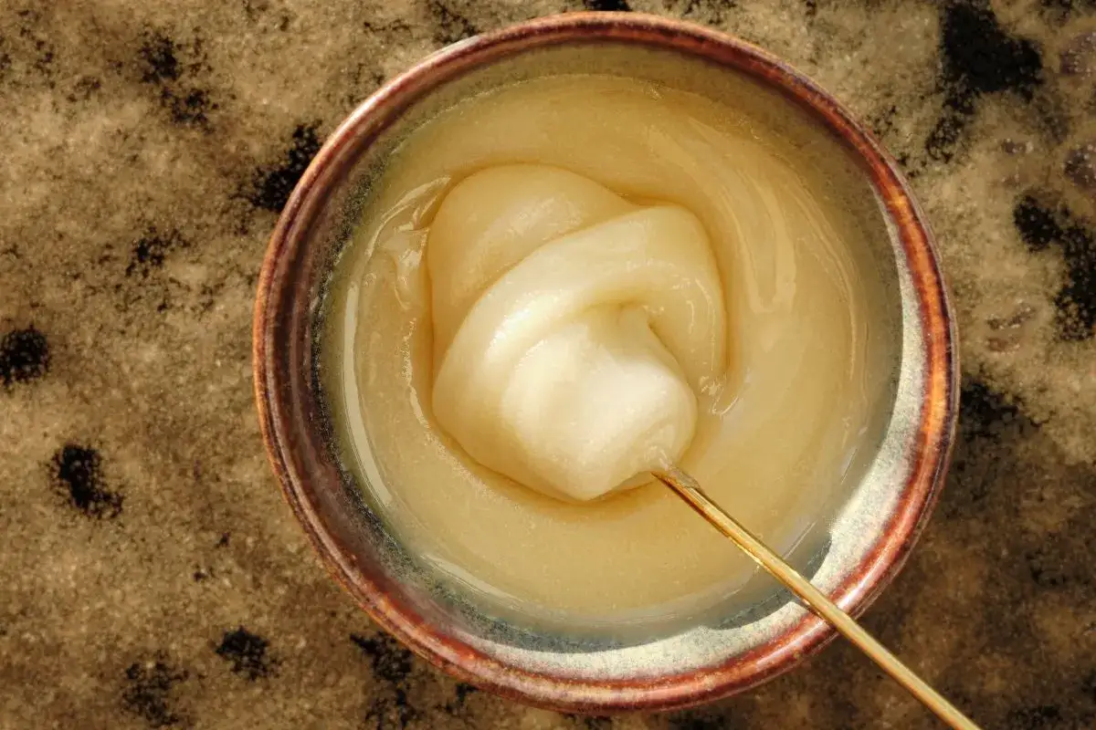 Crema pasticcera densa e lucida in una ciotola, con un bastoncino che ne solleva una porzione. Si può congelare la crema pasticcera per conservarla.