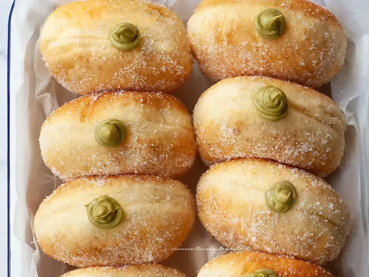 Sei bomboloni soffici, cosparsi di zucchero e guarniti con una deliziosa crema al pistacchio.
