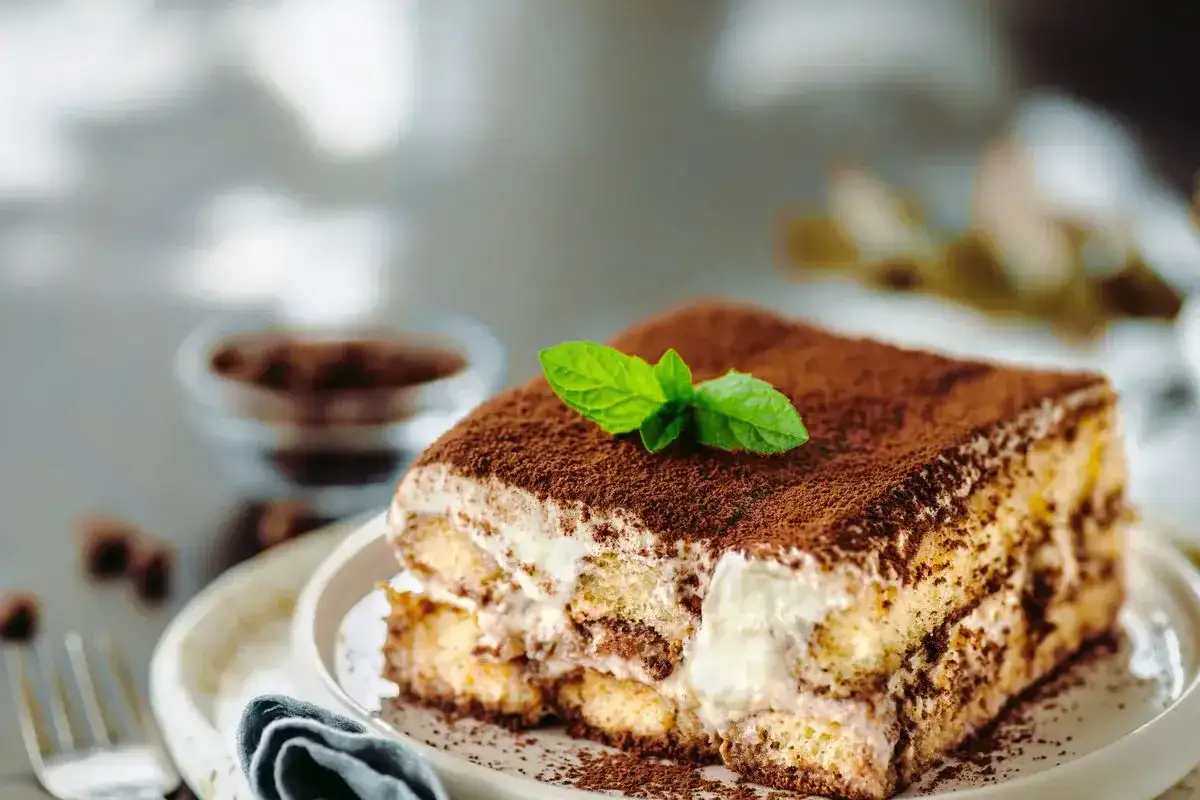 Una fetta di tiramisù, con cacao e menta, pronta per essere gustata. La ricetta perfetta per un dolce indimenticabile.