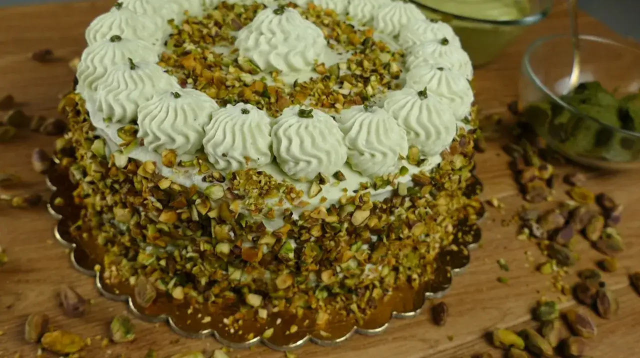 Delizioso dolce con crema al pistacchio, ricoperto di granella di pistacchi e decorato con ciuffi di crema.