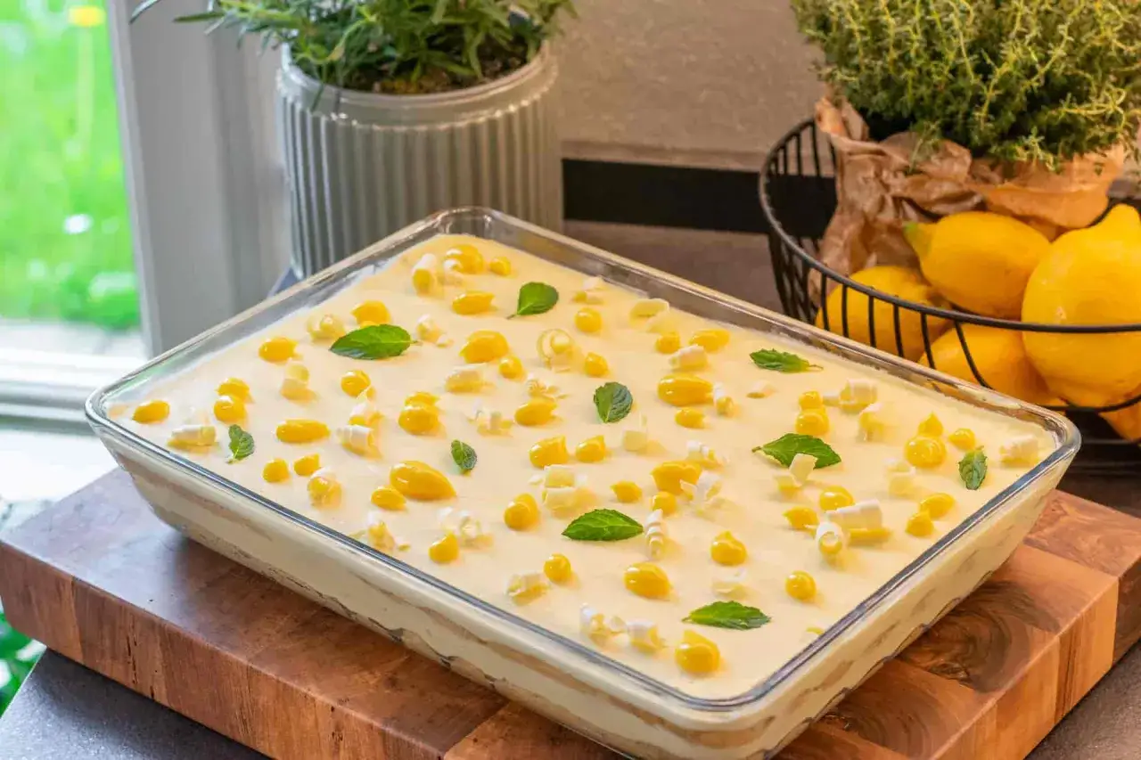 Un delizioso tiramis&ugrave; al limone, guarnito con gocce gialle, riccioli bianchi e foglie di menta fresca.