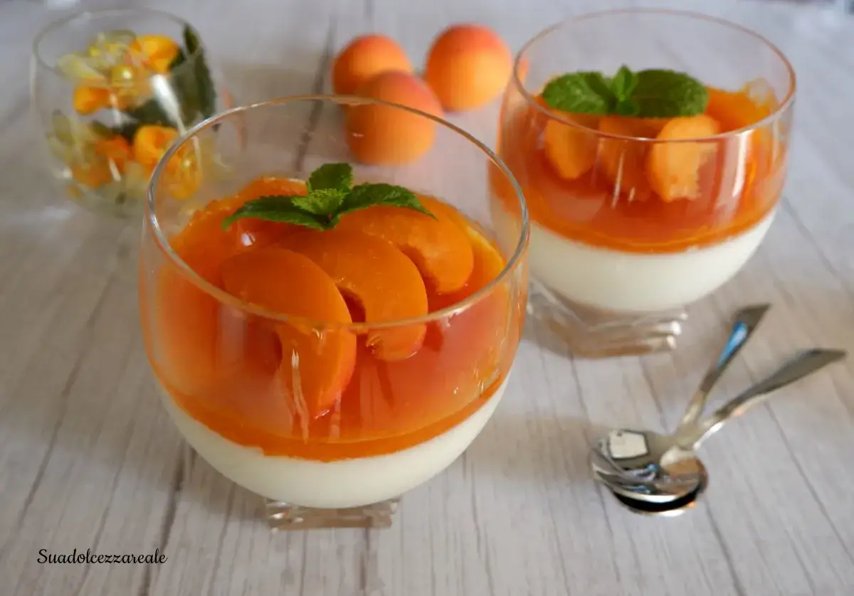 Deliziosa mousse di albicocche in coppette di vetro, guarnita con spicchi di frutta fresca e foglioline di menta.