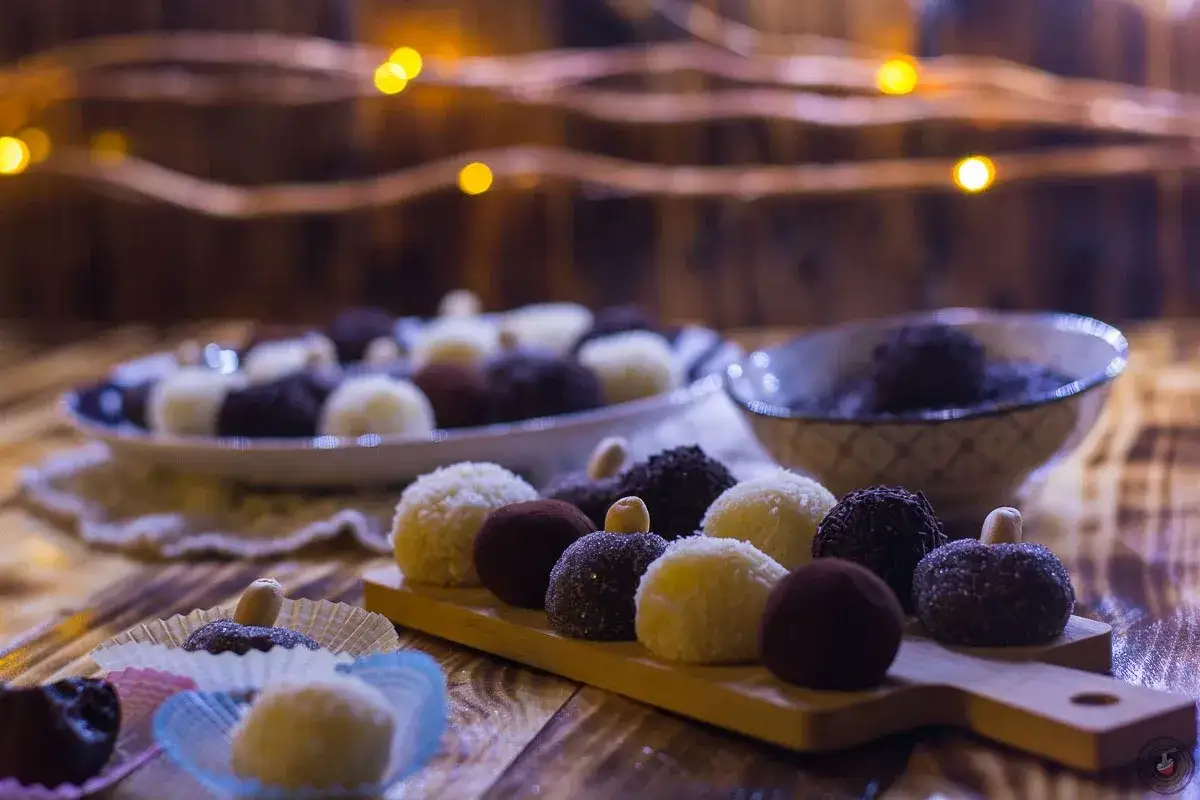 Deliziosi brigadeiro ricetta, dolcetti al cioccolato e cocco, su un tagliere di legno con luci soffuse.