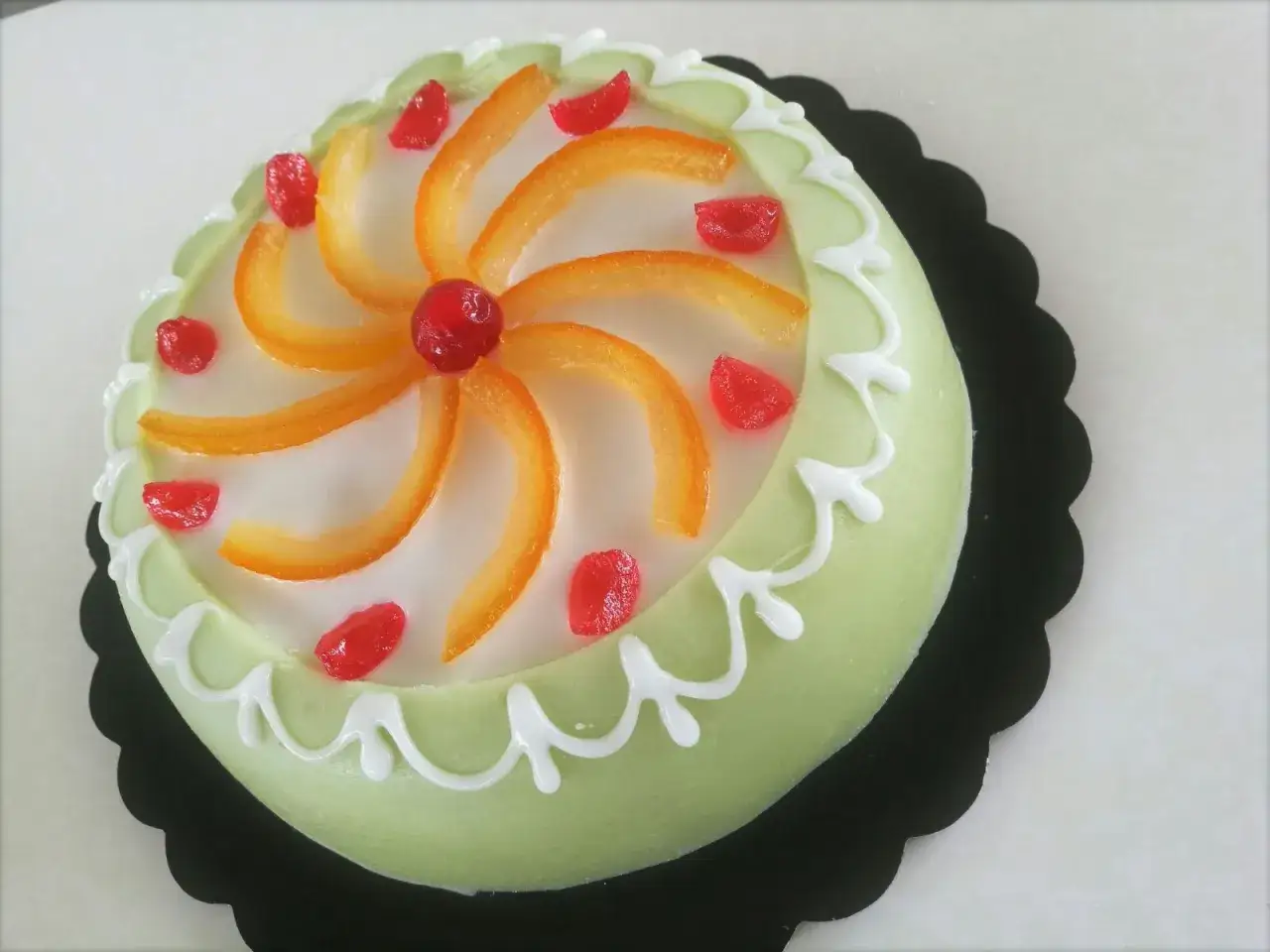 Deliziosa cassata siciliana palermitana, con canditi rossi e scorze d'arancia disposte a raggiera su glassa bianca.