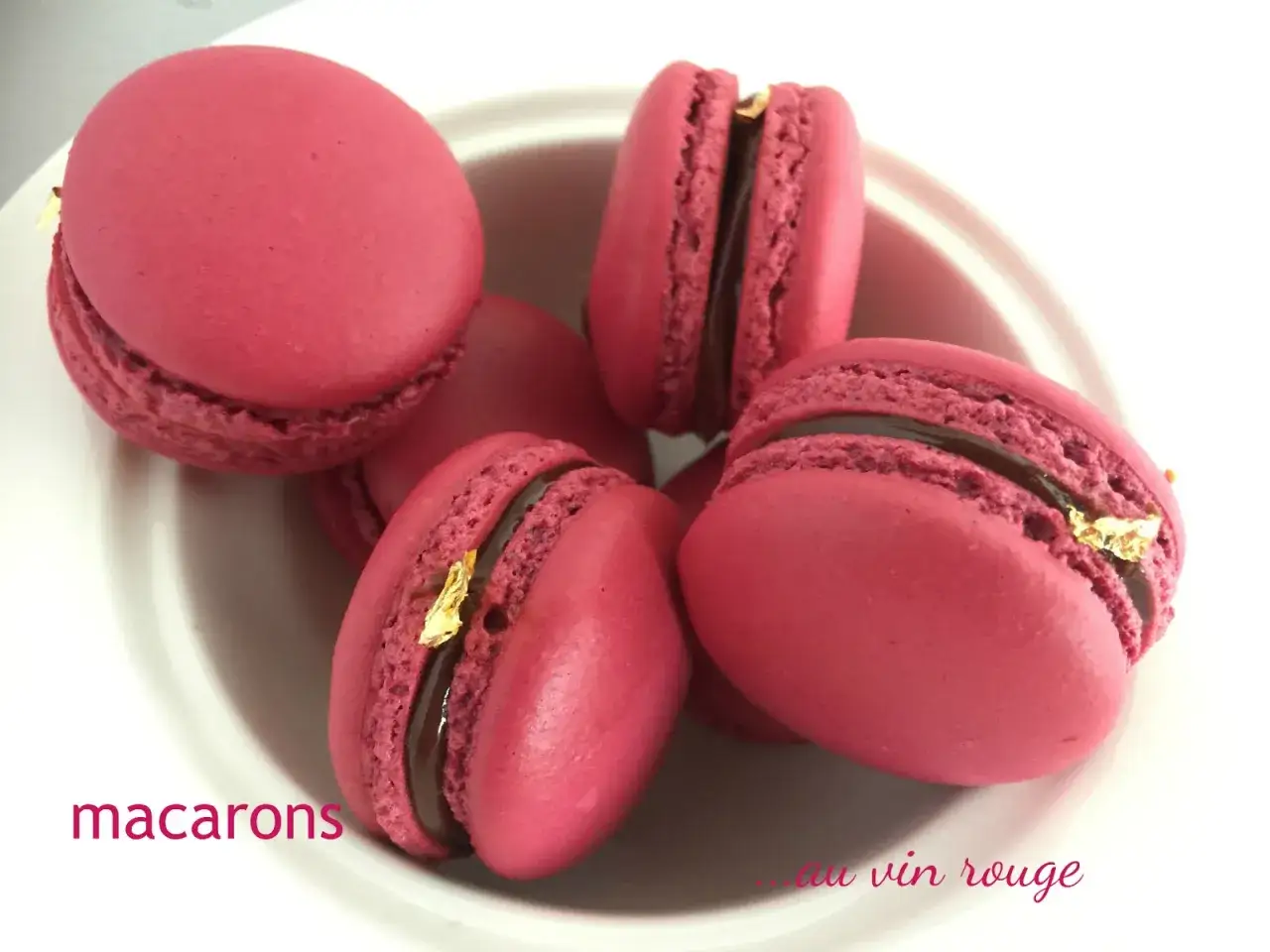 Ecco come sono fatti i macarons: gusci rosa vivaci con ripieno al cioccolato e un tocco d'oro.