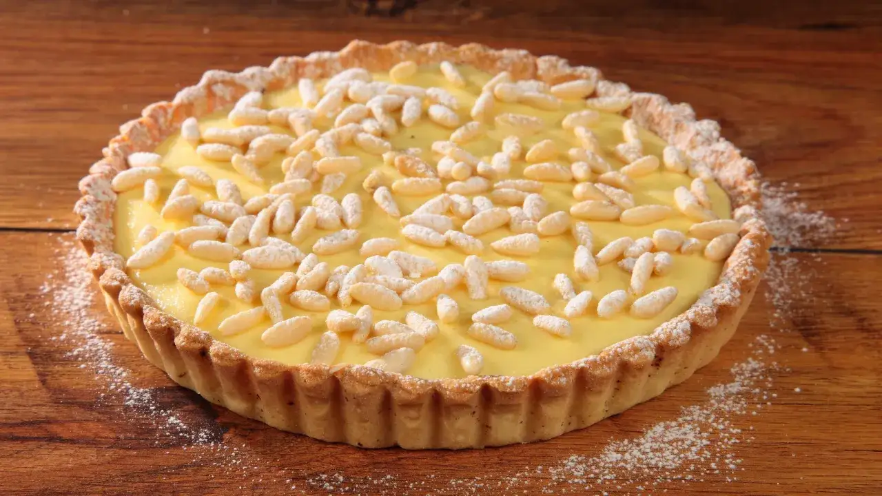 Torta con crema pasticcera e pinoli, un dolce invitante su un tavolo di legno.