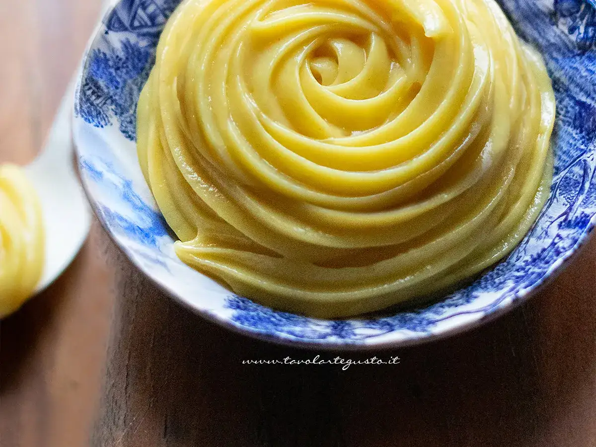 Crema pasticcera senza uova, liscia e vellutata, servita in una ciotola decorata con motivi blu.