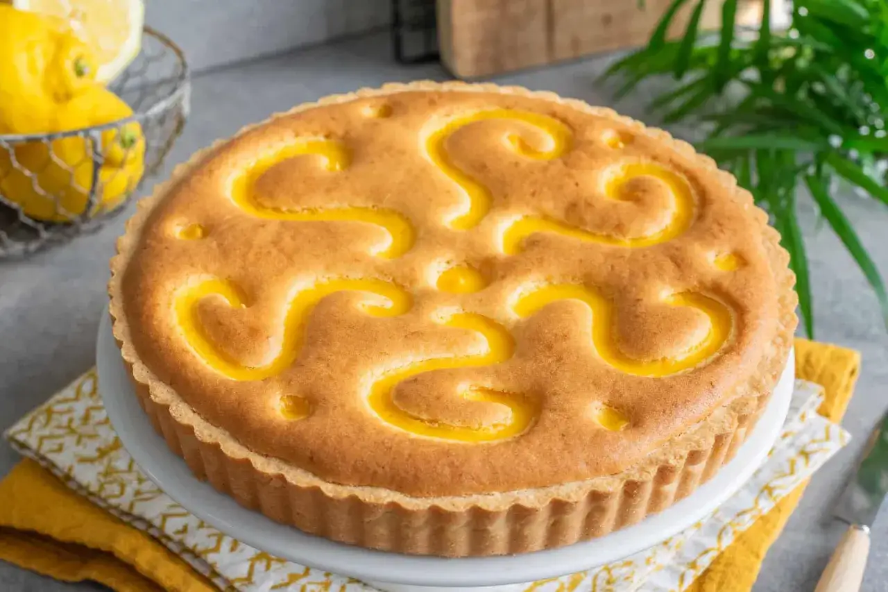 Torta al limone con decorazioni a spirale gialle su una base dorata. Fresca e invitante, pronta per essere gustata.