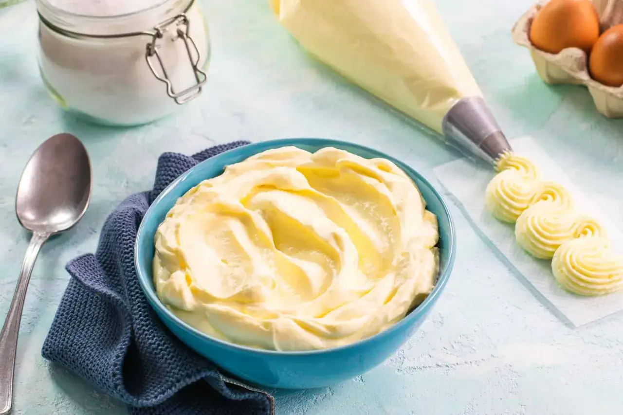 Crema mascarpone pastorizzata pronta per decorare dolci. In una ciotola blu, una generosa porzione di crema, accanto un sac à poche che crea riccioli perfetti.