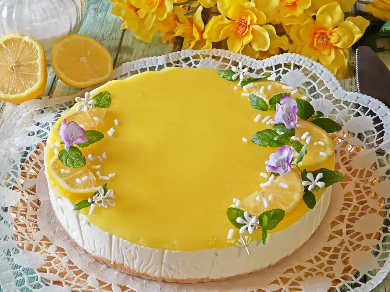 Delizioso cheesecake al limone, decorato con fette di limone, menta e fiori. Un dolce fresco e profumato.