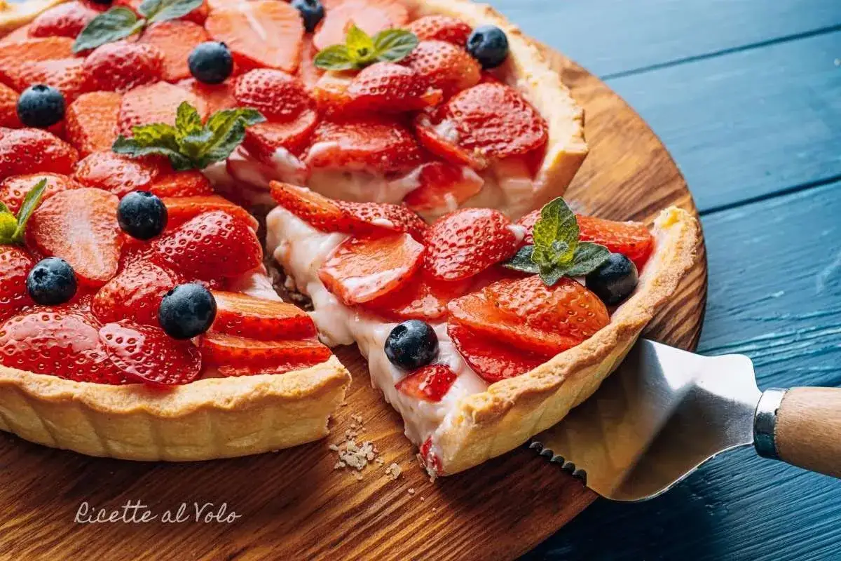 Torta con fragole e mirtilli su base di pasta frolla vegana, guarnita con menta.
