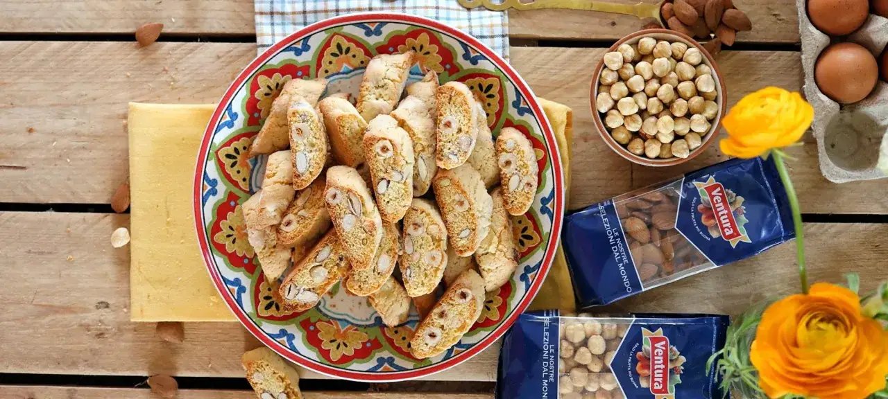 Piatto pieno di tozzetti croccanti con mandorle e nocciole, pronti per essere gustati. La ricetta perfetta per un dolce fatto in casa.