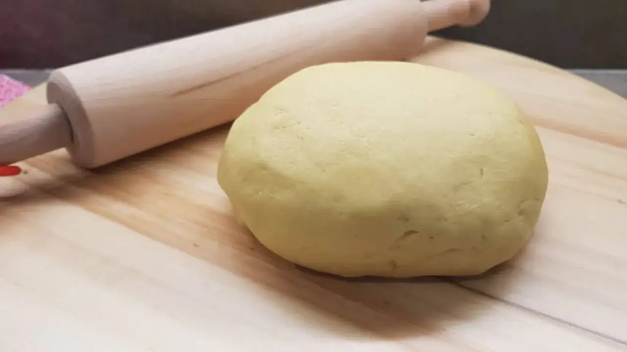 Impasto di pasta frolla pronto per essere steso con il mattarello in legno, per creare dolci deliziosi.