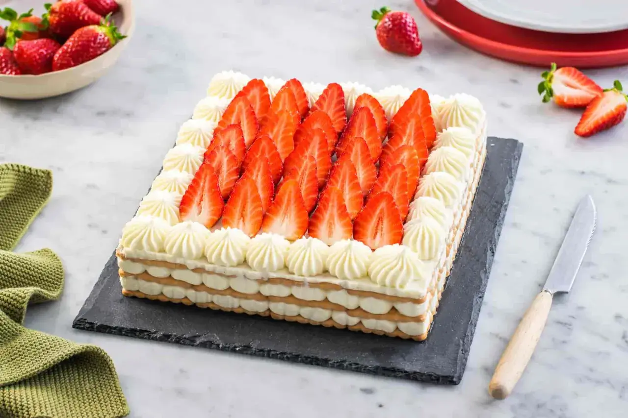 Torta fragole e mascarpone senza cottura, un dolce fresco e goloso. Strati di biscotti e crema al mascarpone, decorata con fragole fresche e ciuffetti di panna.