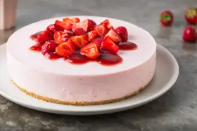 Deliziosa torta fragole e mascarpone senza cottura, guarnita con fragole fresche e salsa rossa.