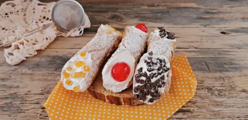 Cannoli siciliani decorati con canditi, ciliegie e gocce di cioccolato, pronti per essere gustati. Ingredienti cannolo siciliano perfetti.